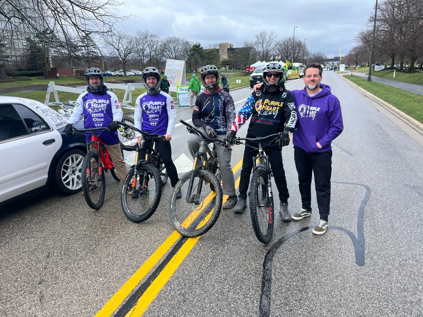 Team members gathered with mountain bikes on a street for a community event